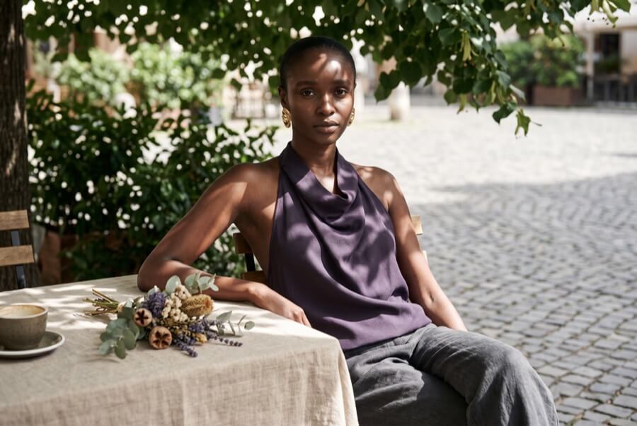 Woman wearing a deep aubergine halterneck top at an outdoor cafe table