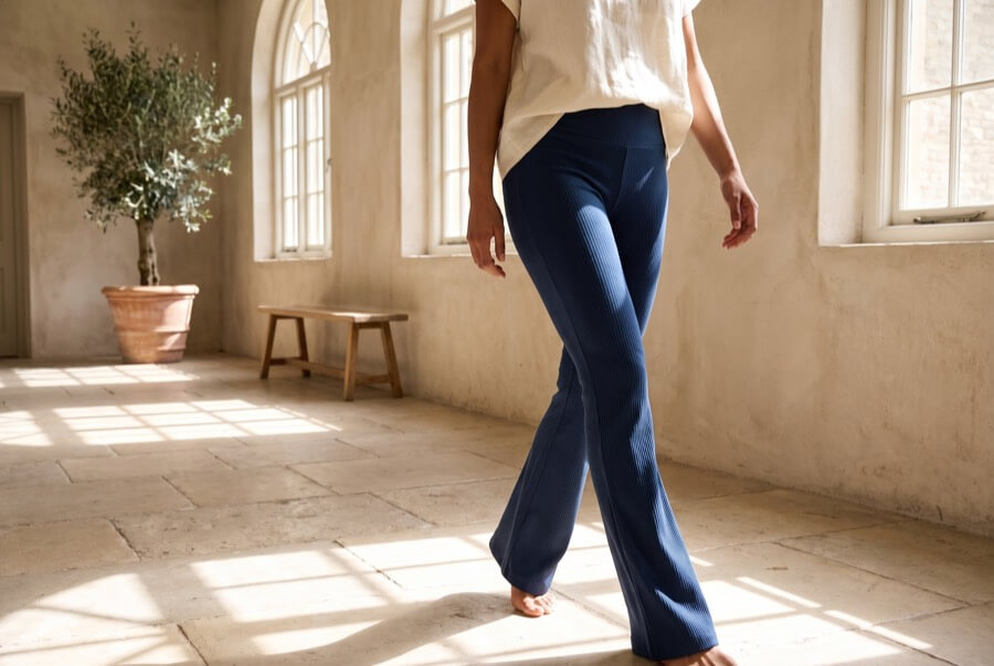 Woman wearing navy ribbed flare trousers in a light-filled corridor