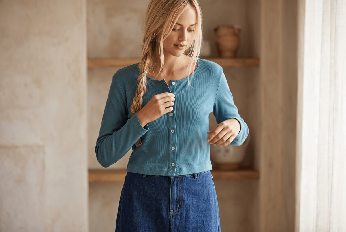Cropped ribbed organic cotton cardigan worn over a denim skirt — sustainable wardrobe staple
