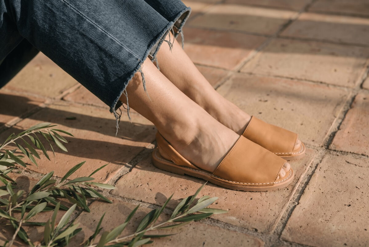 Flat tan leather avarca slide sandals on terracotta tiles — sustainable footwear