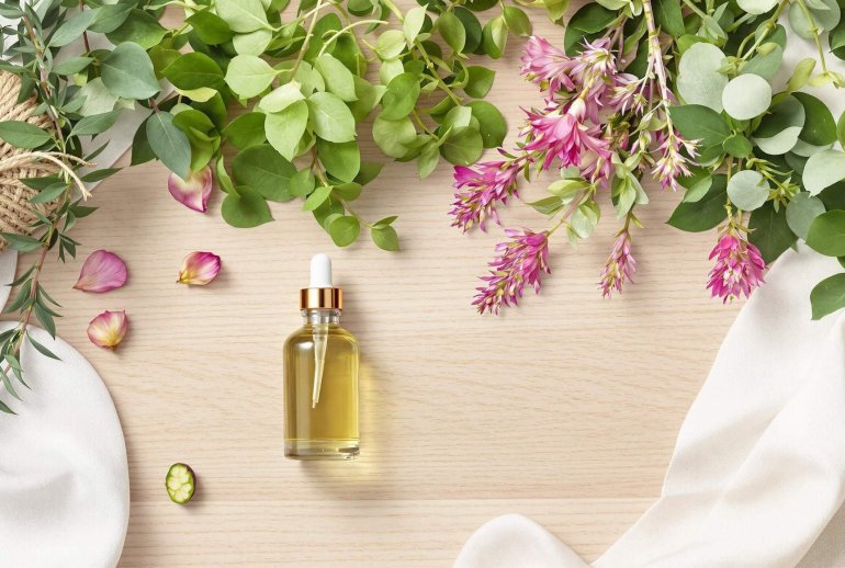 Fresh herbs, aloe, glass bottles, floral essences on wood.