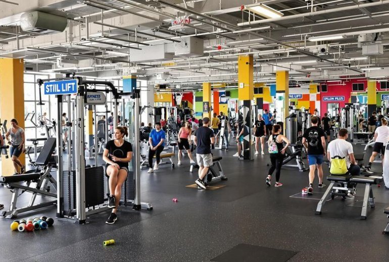 Vibrant fitness center with people exercising and equipment.