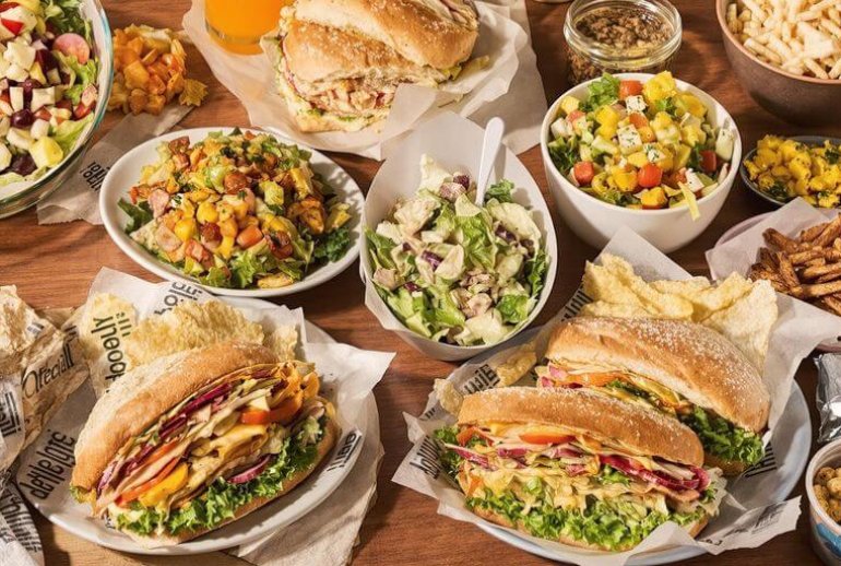 Colorful healthy sandwiches and salads on a wooden table.