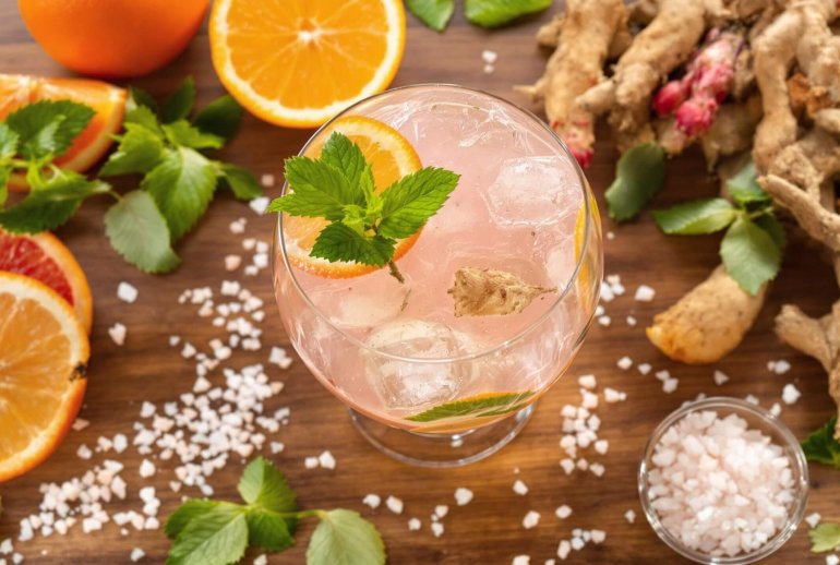 Bare cocktail glass with vibrant natural ingredients on wooden backdrop.